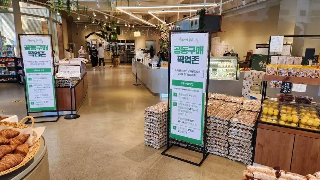 베이커리 카페 안에 설치된 공동구매 픽업존 배너와 달걀 진열